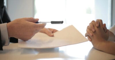 Arbeitsvertrag: Person zeigt Dokument, andere Person hört zu