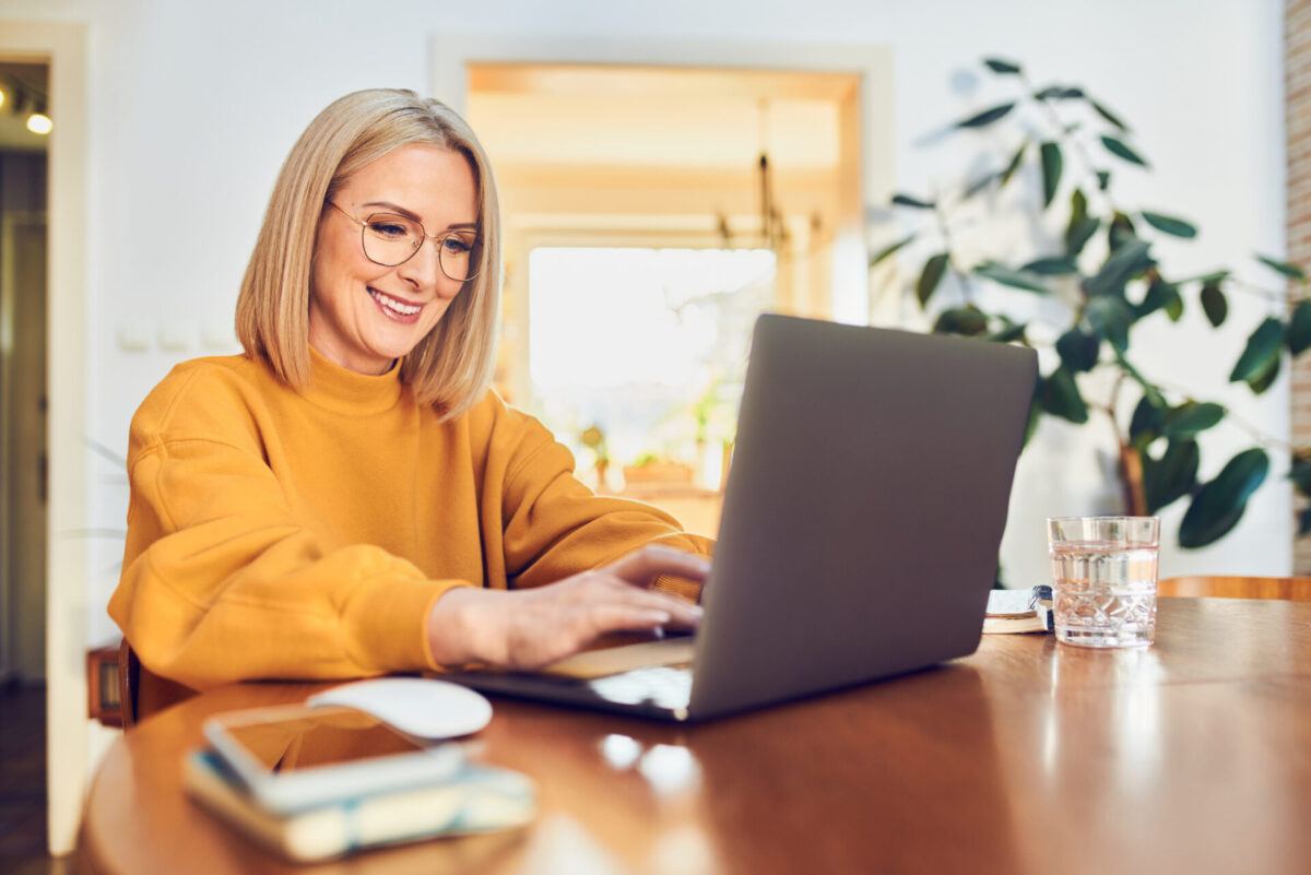 Reife Frau mit Brille arbeitet am Laptop im Homeoffice