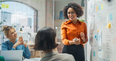 Frau mit Brille erklärt mit Selbstbewusstsein und Kompetenz