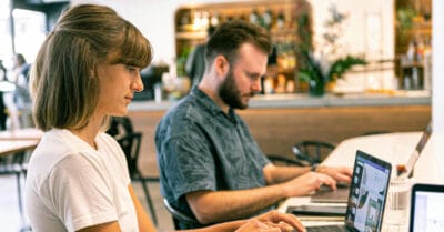 Zwei Personen arbeiten konzentriert an ihren Laptops in einem Café.