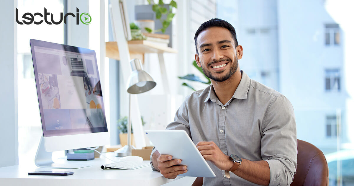 Lächelnder Mann mit Tablet im modernen Büro mit digitalen Geräten